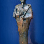 Bronze and gold votive statue of the Egyptian god Osiris wearing the atef crown and holding the crook and flail.
